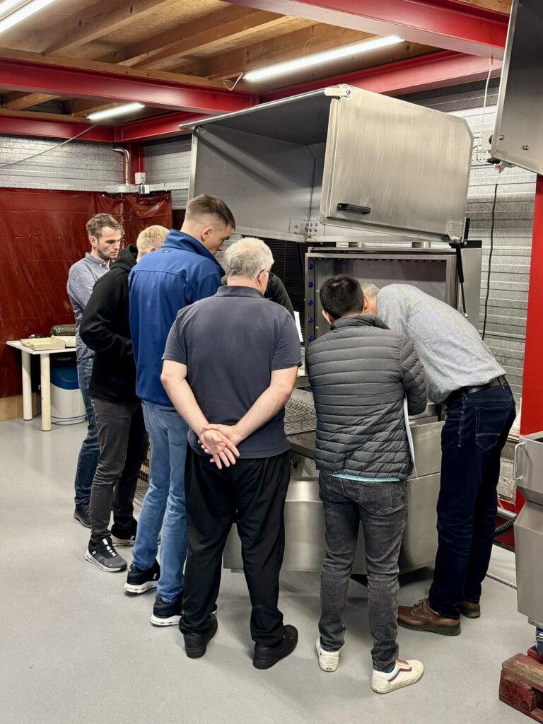 Service training participants looking at a machine, getting instructions from a Harstra instructor